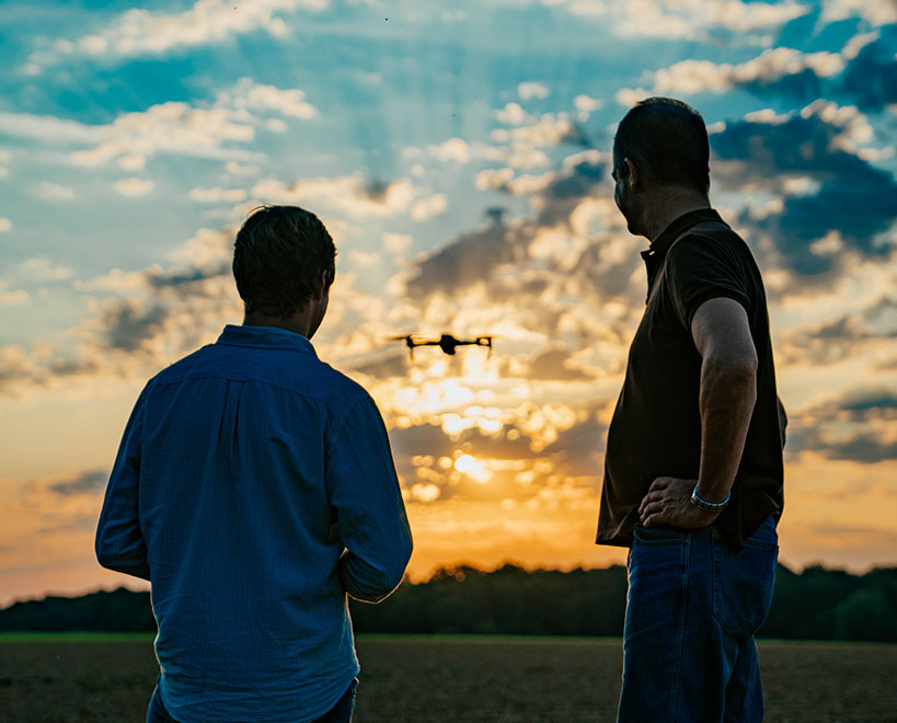 Two people operating a drone. Sun going down.