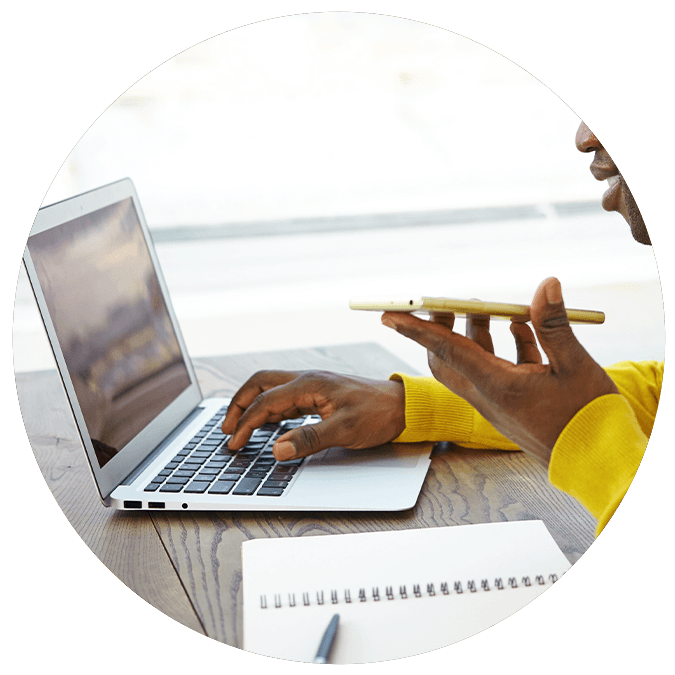 Person on laptop talking into smartphone