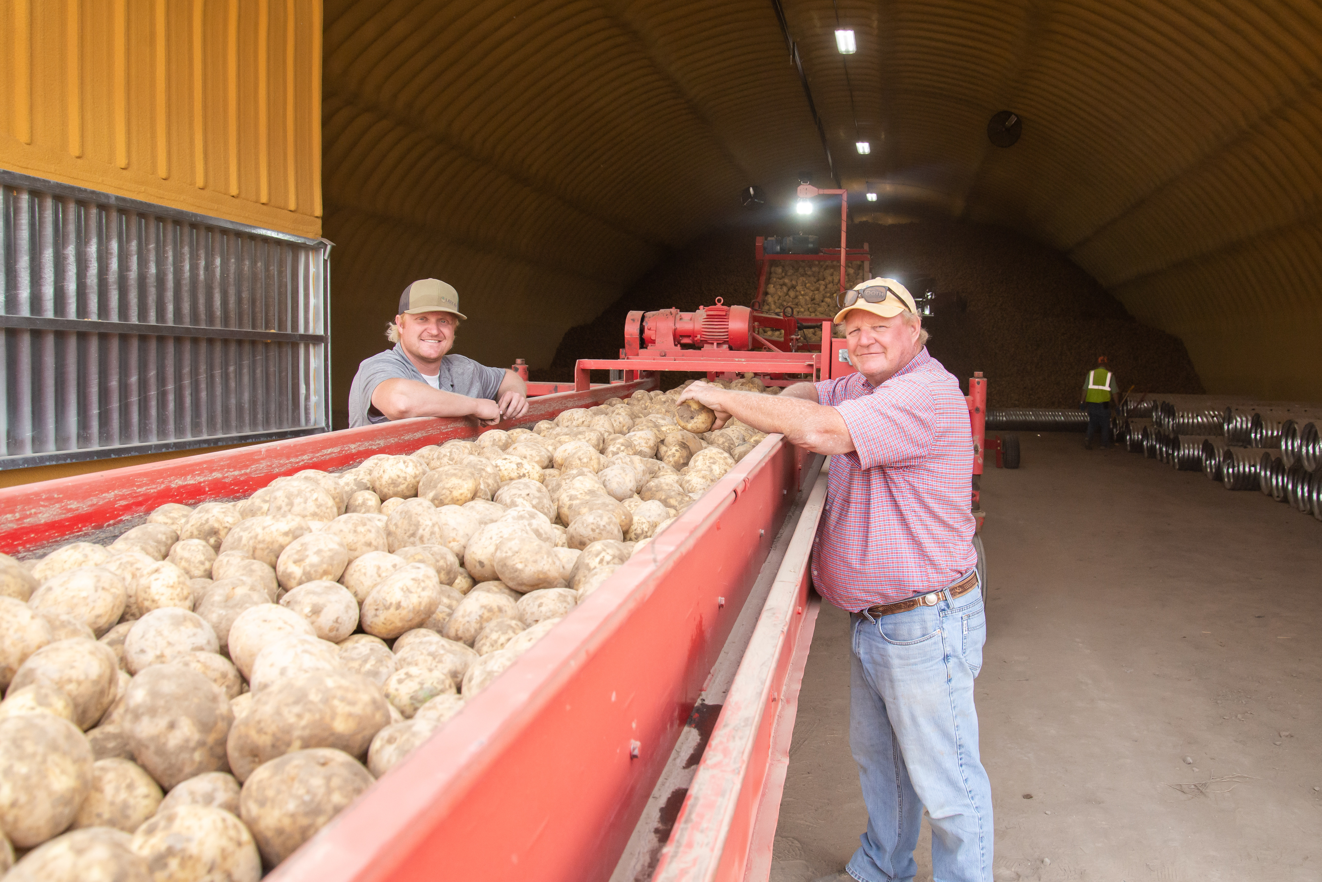 Braden and Rod Lake - two farmers stood with potatoes on farming machinery